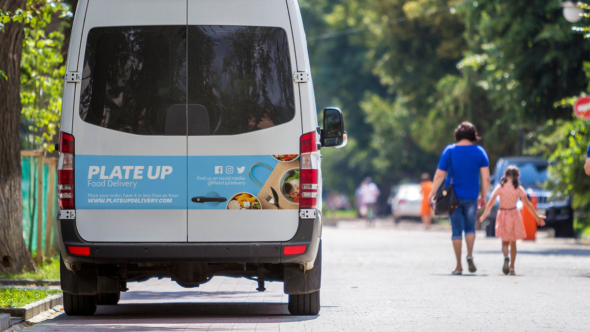Delivery van with a printed wrap panel across its rear doors, conforming around handles and hinges