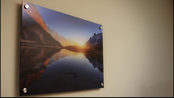 Acrylic sign wall-mounted on standoffs, viewed at an angle to show the clear panel edge