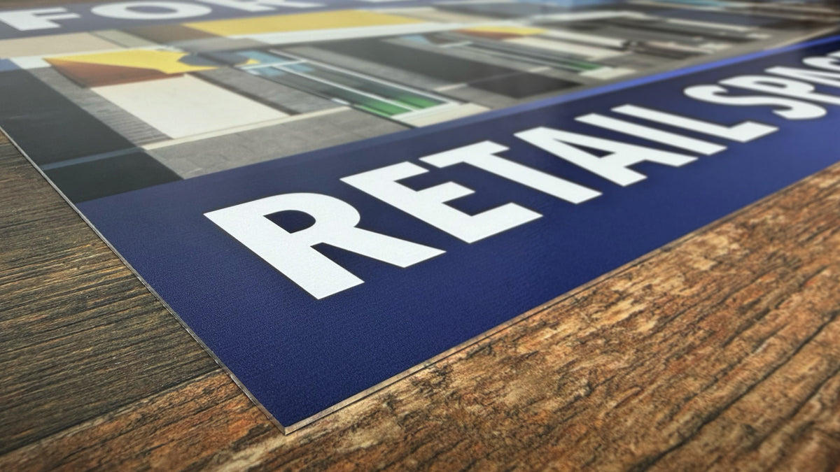 Close-up of an aluminum sign resting on a table, showing the thin rigid panel edge and matte printed surface