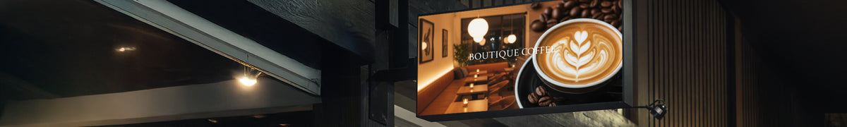 Wide backlit blade sign projecting from a shopfront, lit from within at night