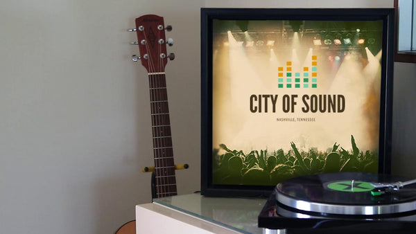 Framed canvas print displayed on a console beside a guitar and turntable