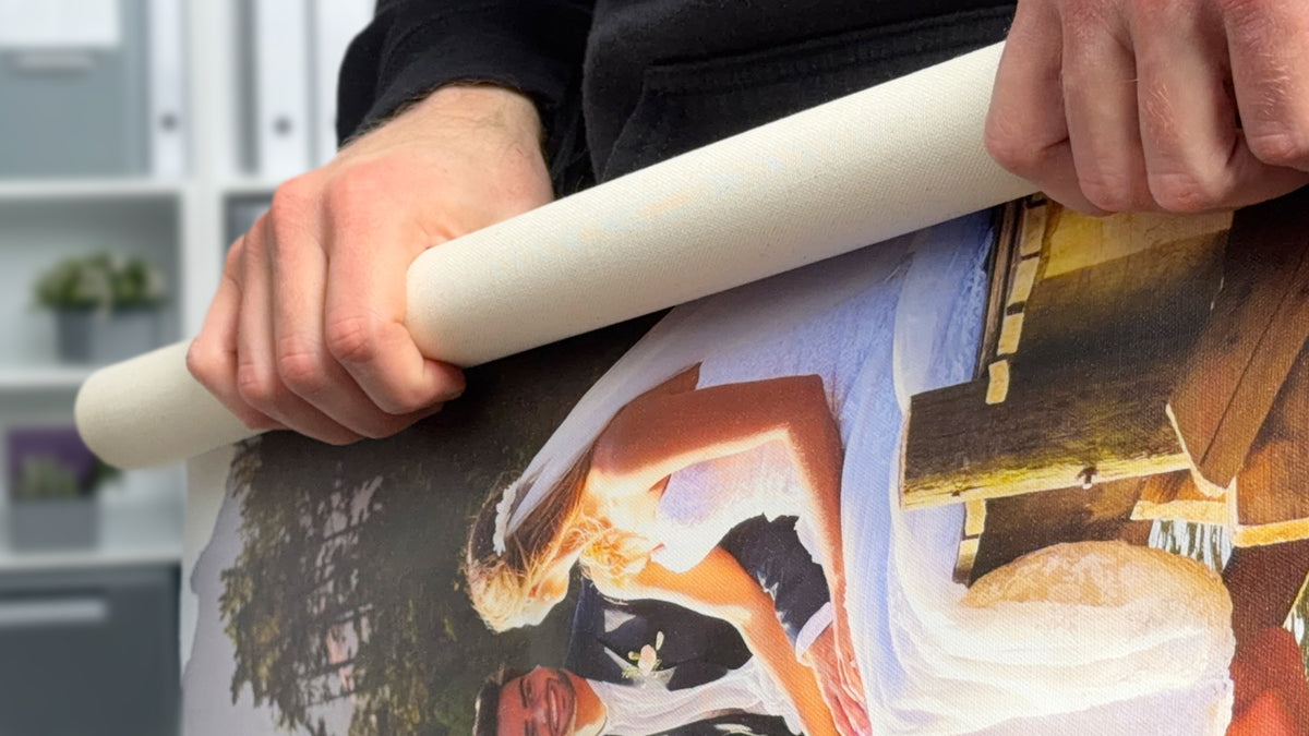 Person unrolling a canvas print, showing the flexible poly-cotton material before stretching