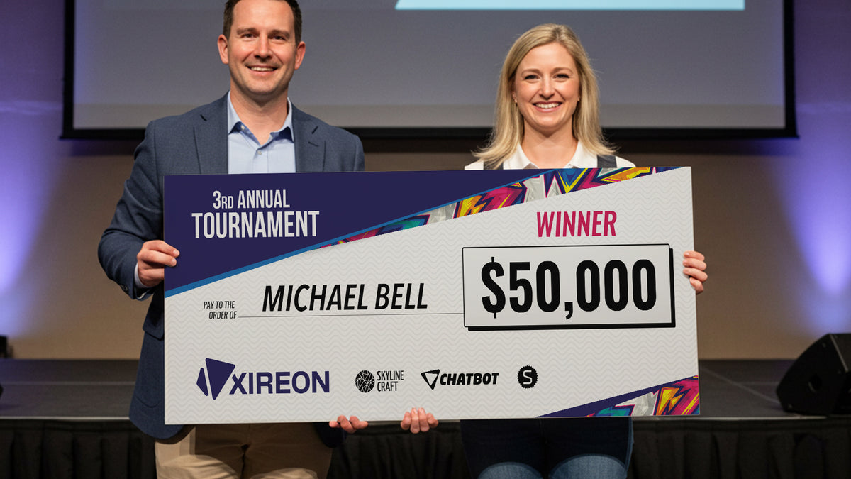 Oversized foam board presentation check held up by two people on a stage