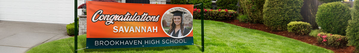 Wide vinyl banner stretched between two ground stakes across a front lawn