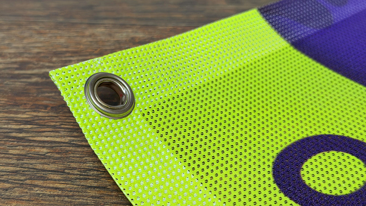 Close-up of a mesh banner corner, showing the open weave of the polyester and a metal grommet